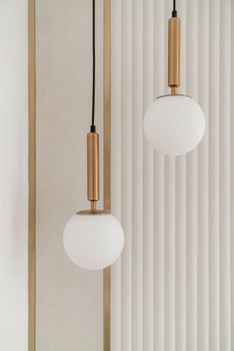 Lampa wisząca w białym wnętrzu z metalowymi akcentami.