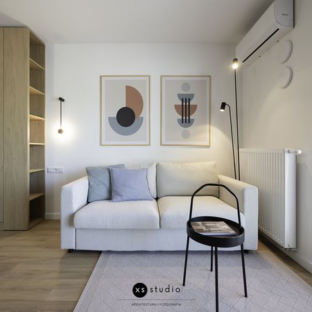 Wnętrze salonu w stylu skandynawskim z jasną sofą i drewnianymi detalami.