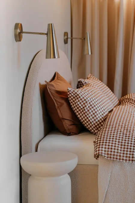 Sypialnia w stylu quiet luxury z beżowym łóżkiem i vintage poduszkami.