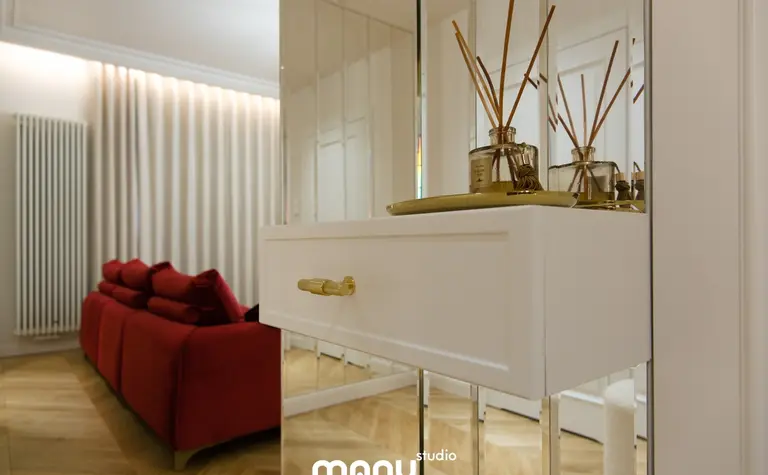 Nowoczesny salon z czerwonymi meblami, białą komodą i dekoracjami.