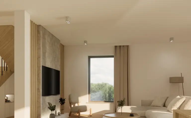 Jasny salon z beżową sofą, kamienną ścianą z telewizorem, oraz okrągłym, drewnianym stolikiem kawowym. Minimalistyczne oświetlenie i duże okno wpuszczają naturalne światło.