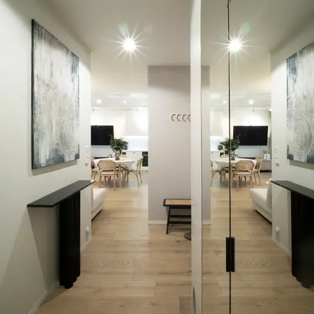 Nowoczesny przedpokój z drewnianą podłogą, jasnymi ścianami i obrazami w stylu quiet luxury.