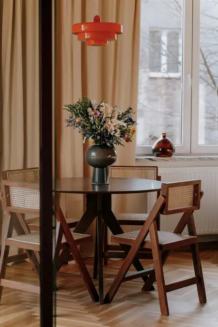 Wnętrze jadalni z drewnianym stołem, krzesłami i bukietem kwiatów, styl quiet luxury.