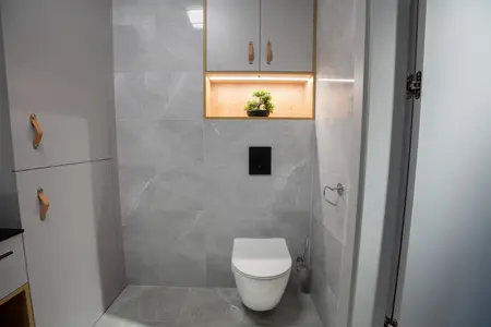 Nowoczesna łazienka z szarymi płytkami i drewnianymi detalami, styl industrialny.