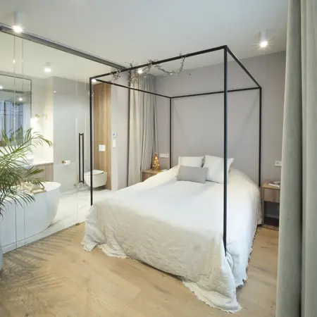 Sypialnia z łóżkiem, drewnianymi detalami i strefą łazienki w stylu quiet luxury.