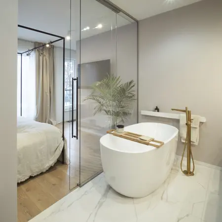 Nowoczesna łazienka z wolnostojącą wanną, drewnianymi detalami i roślinnością w stylu quiet luxury.