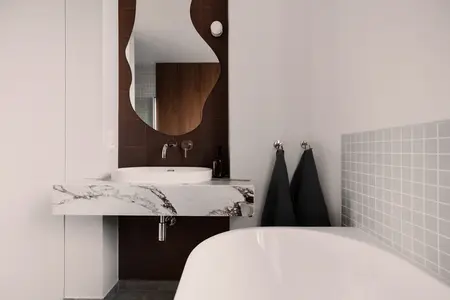 Nowoczesna łazienka z marmurową umywalką, lustrem i szarymi płytkami. Quiet luxury, soft minimalizm, vintage.