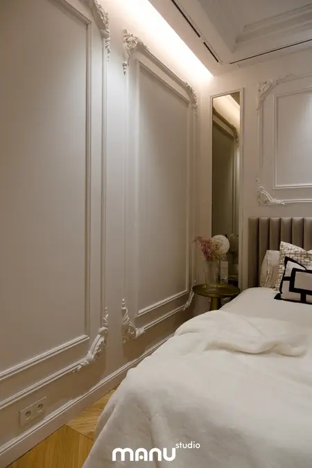 Wnętrze sypialni z jasnymi ścianami, drewnianą podłogą i eleganckimi detalami.