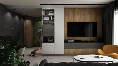 Wnętrze nowoczesnego salonu z telewizorem, drewnianymi elementami i roślinami.
