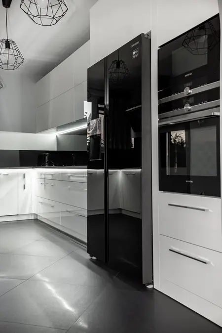 Nowoczesna kuchnia z białymi meblami i czarnym sprzętem, minimalistyczny design.