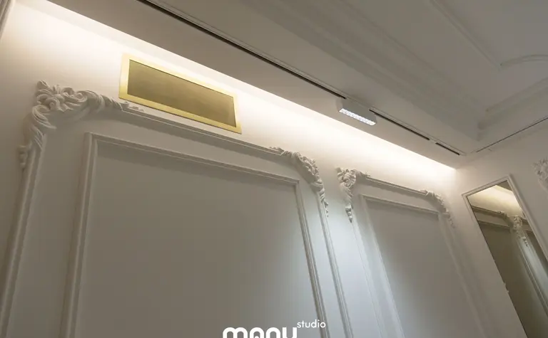 Stylowe wnętrze z białymi ścianami, złotymi akcentami i klasycznymi detalami.