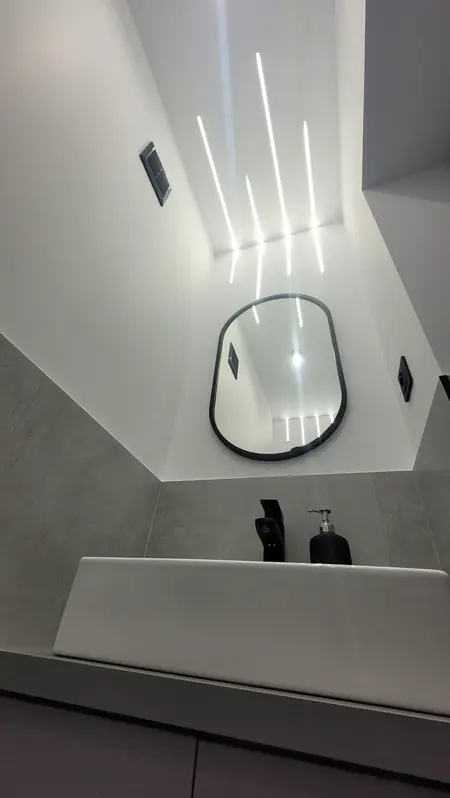 Minimalistyczna łazienka z białą umywalką i szarymi akcentami.