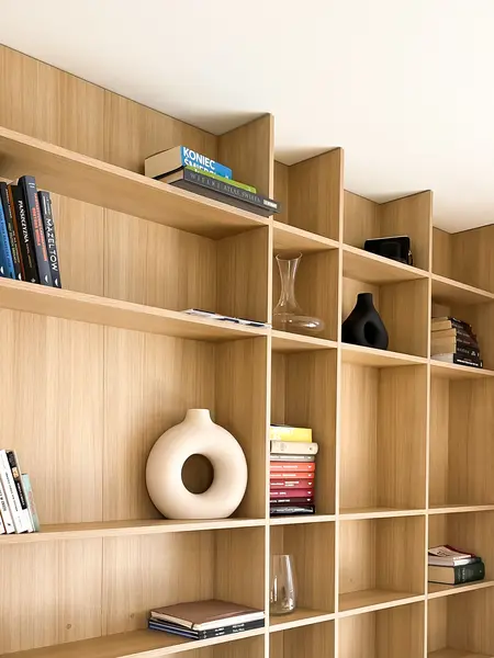 Minimalistyczne wnętrze z półkami, książkami i dekoracjami w stylu soft minimalizm.