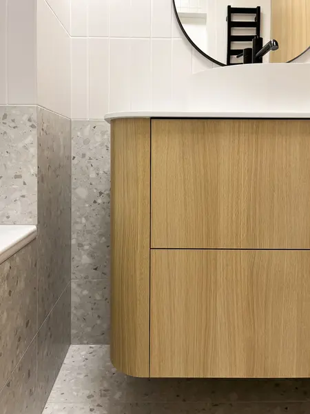 Minimalistyczna łazienka z drewnianą szafką i białą umywalką w stylu soft minimalizm.