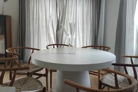 Wnętrze jadalni w stylu boho, japandi i minimalistycznym z białym stołem.