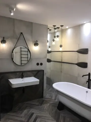 Nowoczesna łazienka glamour z białą wanną i szarymi ścianami.