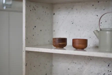 Minimalistyczne wnętrze z boho akcentami, drewniane naczynia na półce.