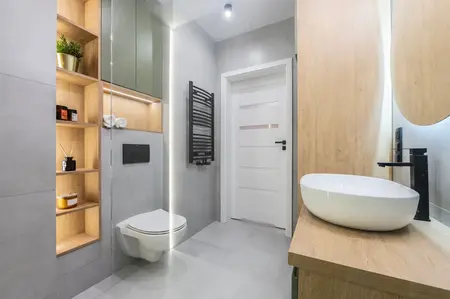 Wnętrze łazienki z drewnianymi meblami i nowoczesnymi detalami w stylu industrialnym i współczesnym.