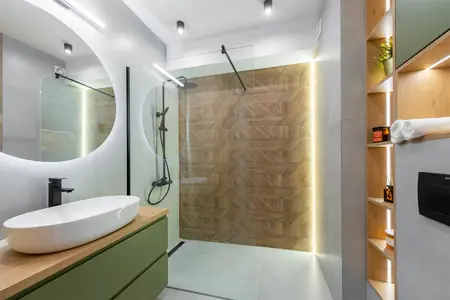 Nowoczesna łazienka z drewnianą ścianą, zielonymi meblami i minimalistycznym designem.
