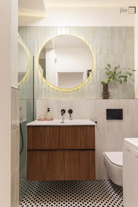 Nowoczesna łazienka z drewnianą szafką, okrągłym lustrem, płytkami w stylu art deco i eklektycznymi akcentami.