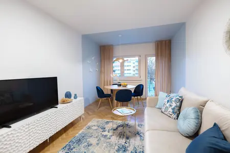 Wnętrze salonu z niebieskimi fotelami i białą sofą, nowoczesny design.