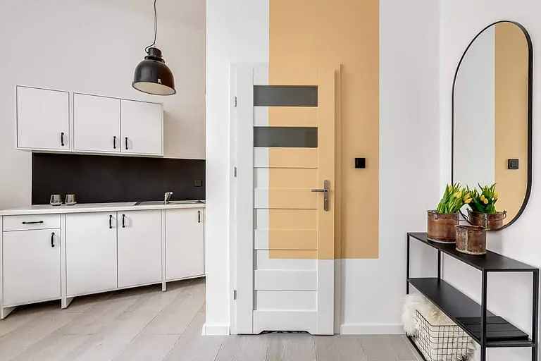 Wnętrze kuchni z białymi szafkami i czarnym blatem, industrialny styl