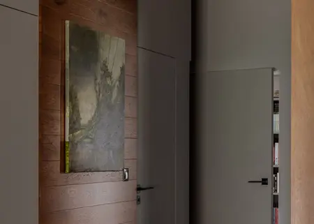 Korytarz z minimalistycznym wystrojem, nowoczesnym obrazem na ścianie i drewnianą okładziną.