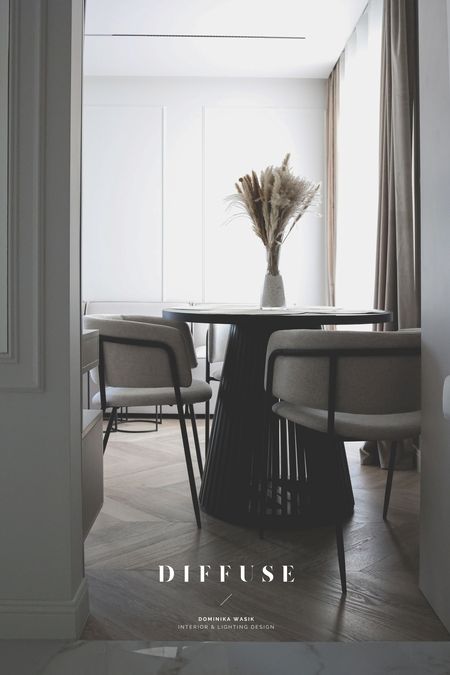 Jadalnia w stylu boho i minimalistycznym z okrągłym stołem i szarymi krzesłami.