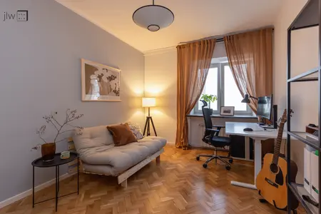 Wnętrze salonu w stylu art deco i skandynawskim z jasną sofą i biurkiem.