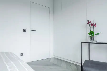 Minimalistyczne wnętrze z białymi ścianami i storczykiem w doniczce.