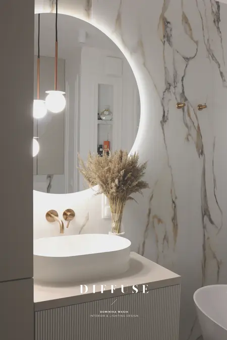 Nowoczesna łazienka z okrągłym lustrem, minimalistycznym designem i akcentami boho.