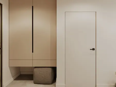 Minimalistyczny przedpokój z beżową szafą i nowoczesnymi drzwiami.