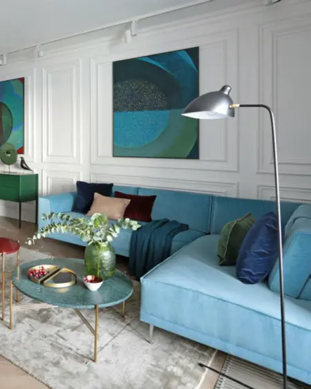 Wnętrze salonu w stylu minimaluxe i quiet luxury z niebieską sofą i zielonymi dodatkami.
