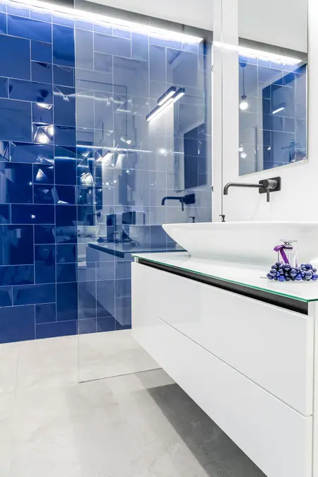Nowoczesna łazienka z niebieskimi płytkami, białą umywalką i minimalistycznym designem