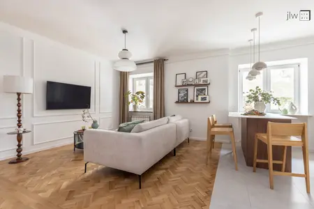 Wnętrze salonu w stylu art deco i skandynawskim z jasnymi meblami i drewnianą podłogą.