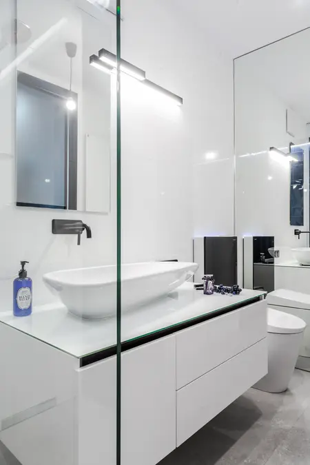 Nowoczesna łazienka z białą umywalką i czarnymi detalami, minimalistyczny design.