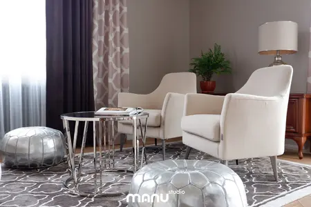 Wnętrze salonu z beżowymi fotelami, szklanym stolikiem i rośliną, styl tradycyjny.