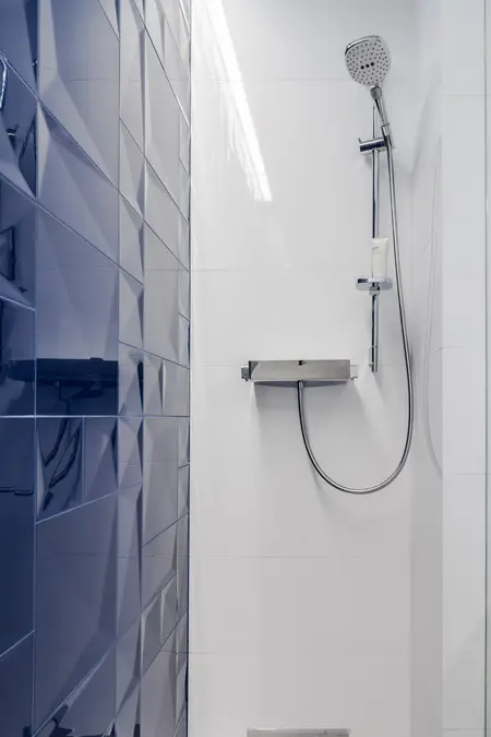 Kabina prysznicowa z niebieskimi i białymi płytkami w stylu minimalistycznym.