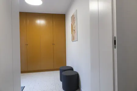 Przedpokój z szafą, szarymi siedziskami i nowoczesnym oświetleniem