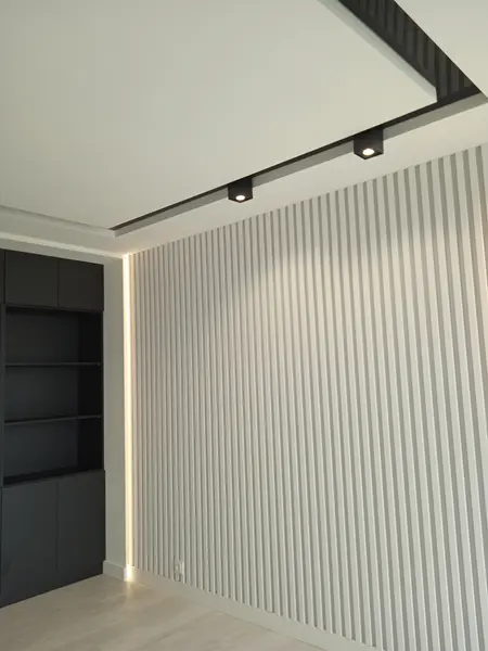 Minimalistyczny i nowoczesny pokój z paskowanym sufitem i czarną szafką.