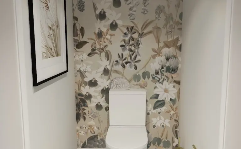 Toaleta z białą ceramiką, kwiecistą tapetą w stylu prowansalskim, czarno-biała podłoga.