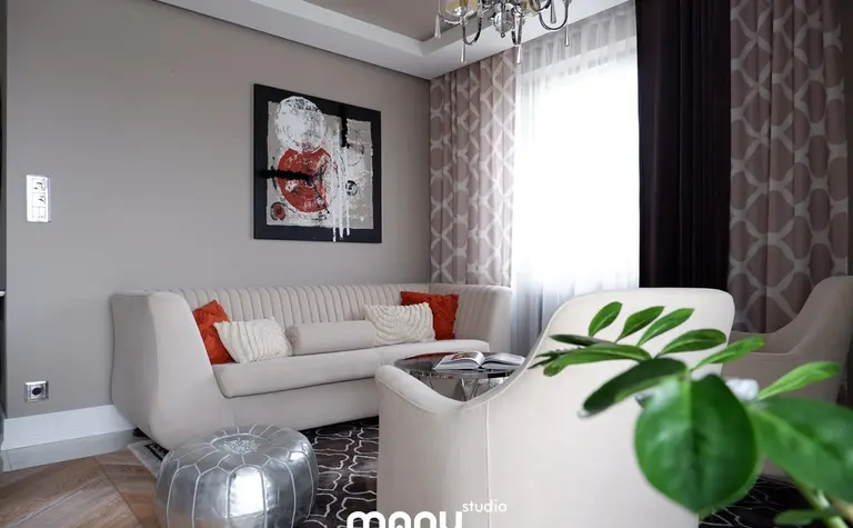 Nowoczesny salon z jasną sofą, czerwonymi poduszkami i dekoracyjnym obrazem. Styl tradycyjny.