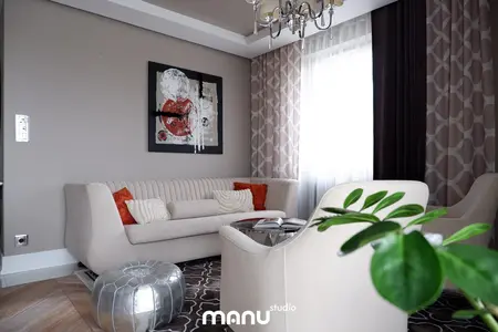 Nowoczesny salon z jasną sofą, czerwonymi poduszkami i dekoracyjnym obrazem. Styl tradycyjny.