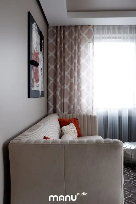 Wnętrze salonu w stylu tradycyjnym z beżową sofą i zasłonami.