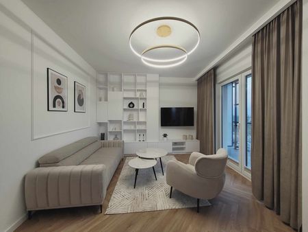 Nowoczesny salon z jasną sofą, szklanym stolikiem i drewnianą podłogą.