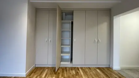 Garderoba z szarymi meblami, drewnianą podłogą w stylu eklektycznym, skandynawskim i współczesnym.