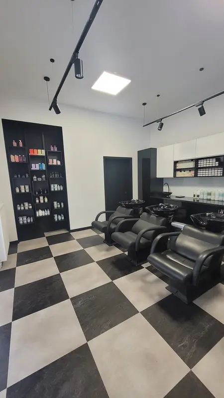 Wnętrze salonu fryzjerskiego z czarnymi fotelami i białymi meblami, styl industrialny i nowoczesny.