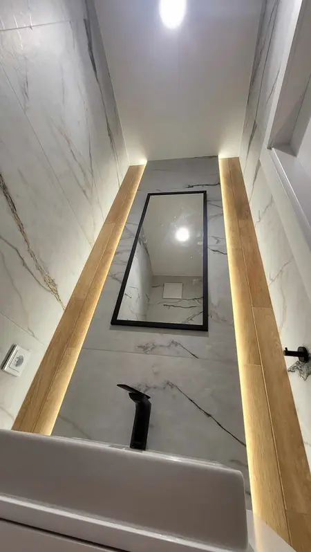 Wnętrze łazienki z marmurowymi ścianami i drewnem, minimalistyczny design.