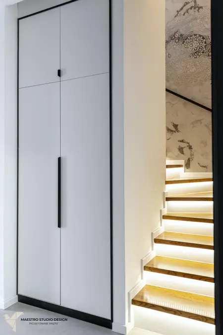 Przestrzeń z białą szafą i drewnianymi schodami, nowoczesny design.