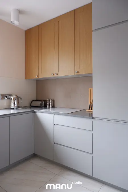 Nowoczesna kuchnia z drewnianymi szafkami i szarymi meblami w stylu tradycyjnym.